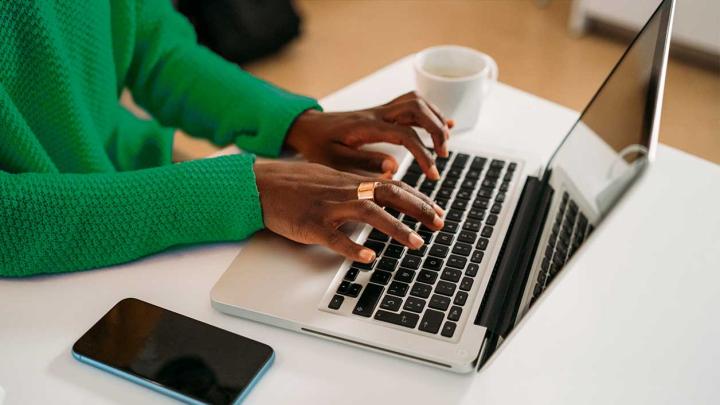 Hands type on a laptop