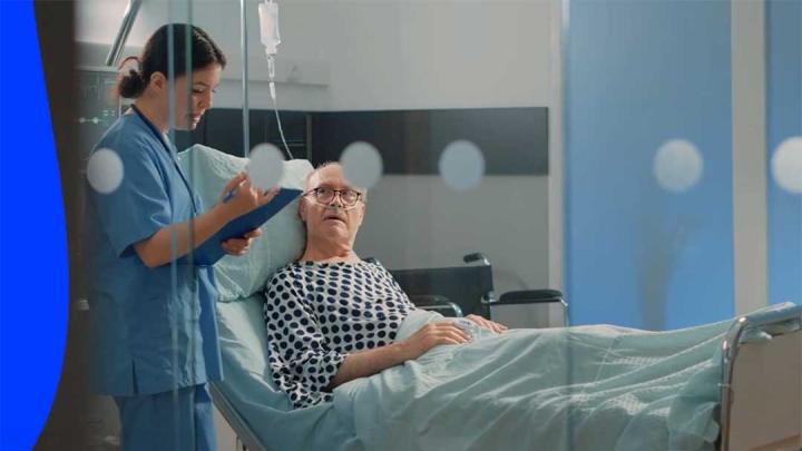 A medical professional attends to a patient resting in a hospital bed