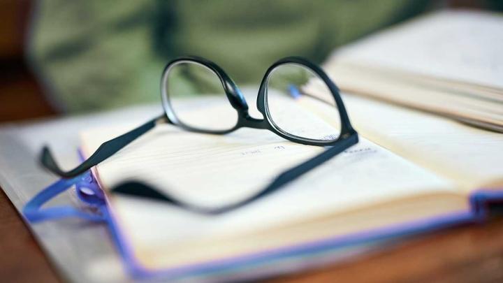 A pair of glasses sits on an open notebook