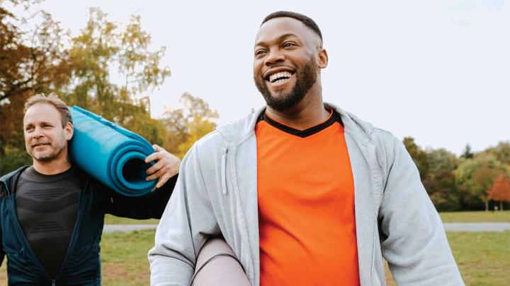 Two men carry exercise mats