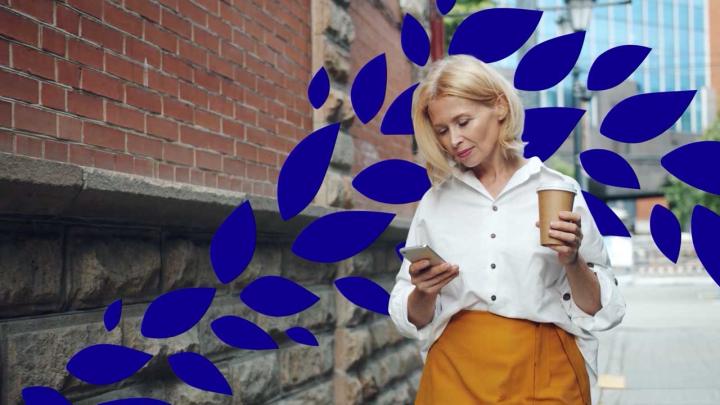 A woman holds a cup and uses a smartphone