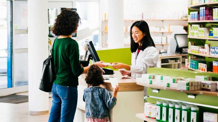 A woman and child receive a prescription item from a pharmacist
