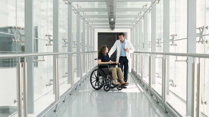 A doctor speaks with a patient who is in a wheelchair