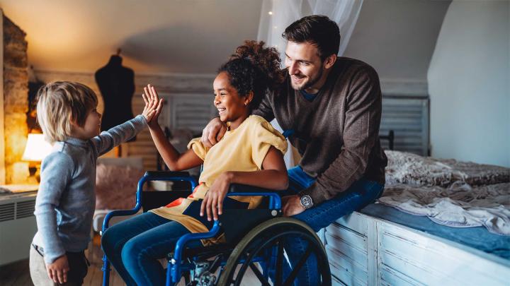 A child in a wheelchair high-fives another child