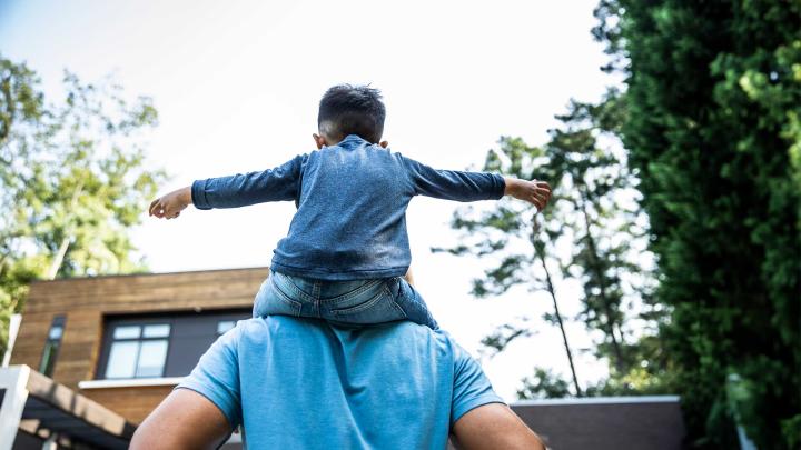 A child sits on a parent's shoulders