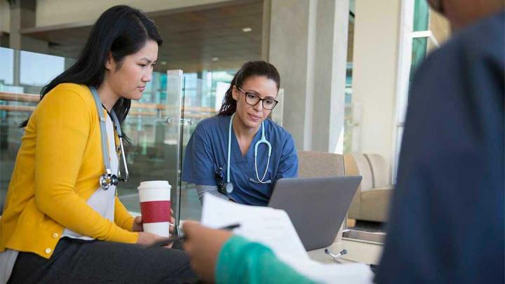 Medical professionals review content on a laptop