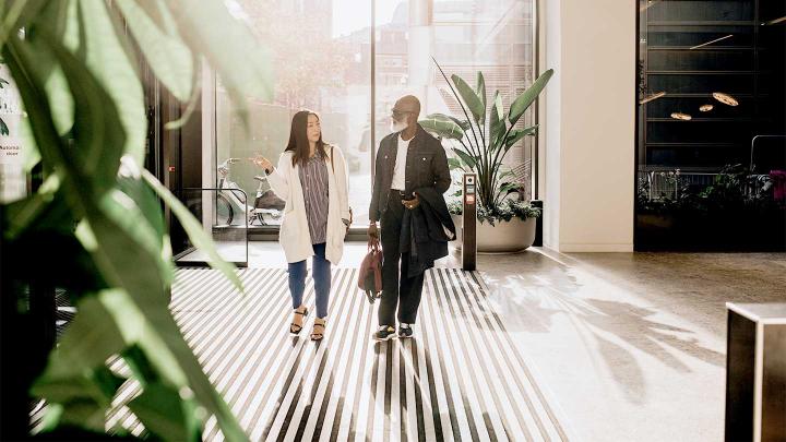 Two colleagues walk together in a lobby