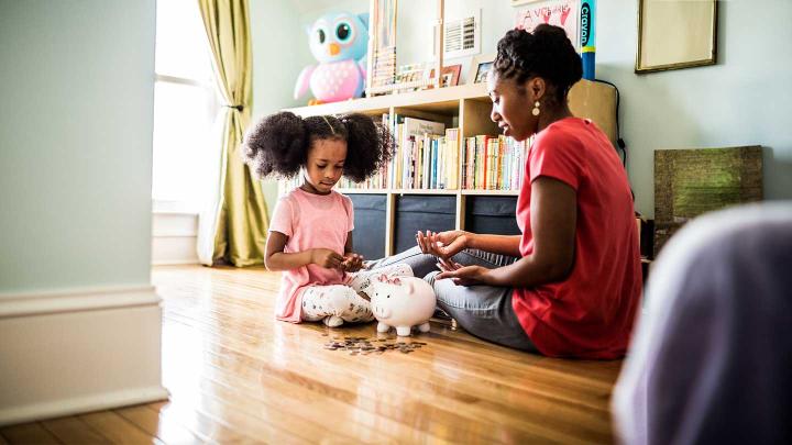 A parent helps a child count their savings from their piggy bank
