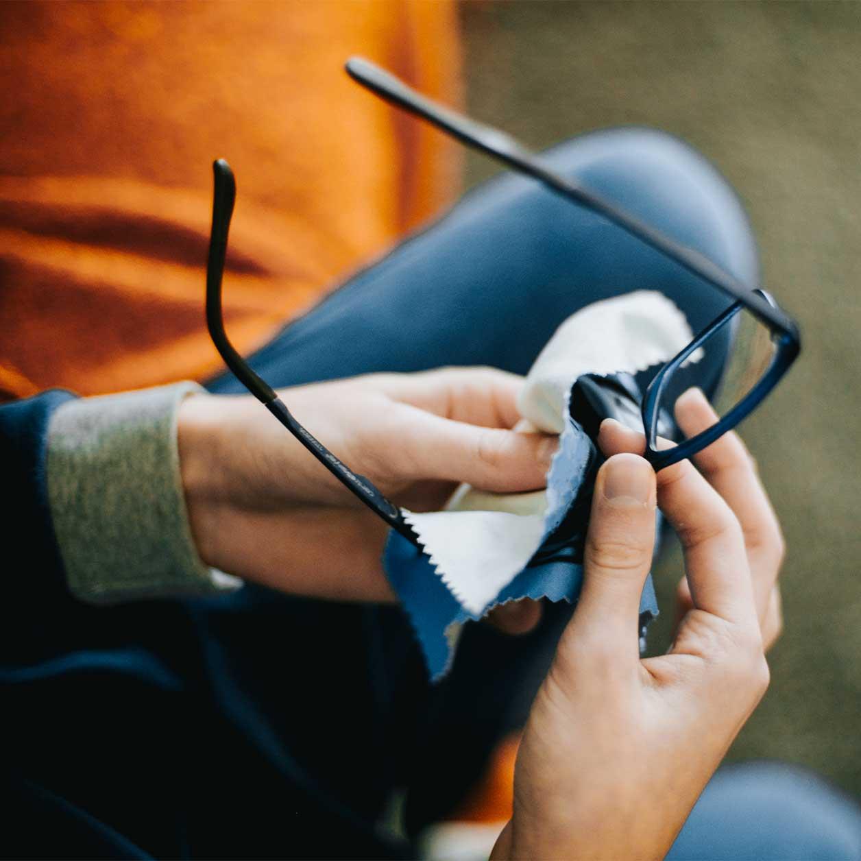 A person cleans a pair of glasses