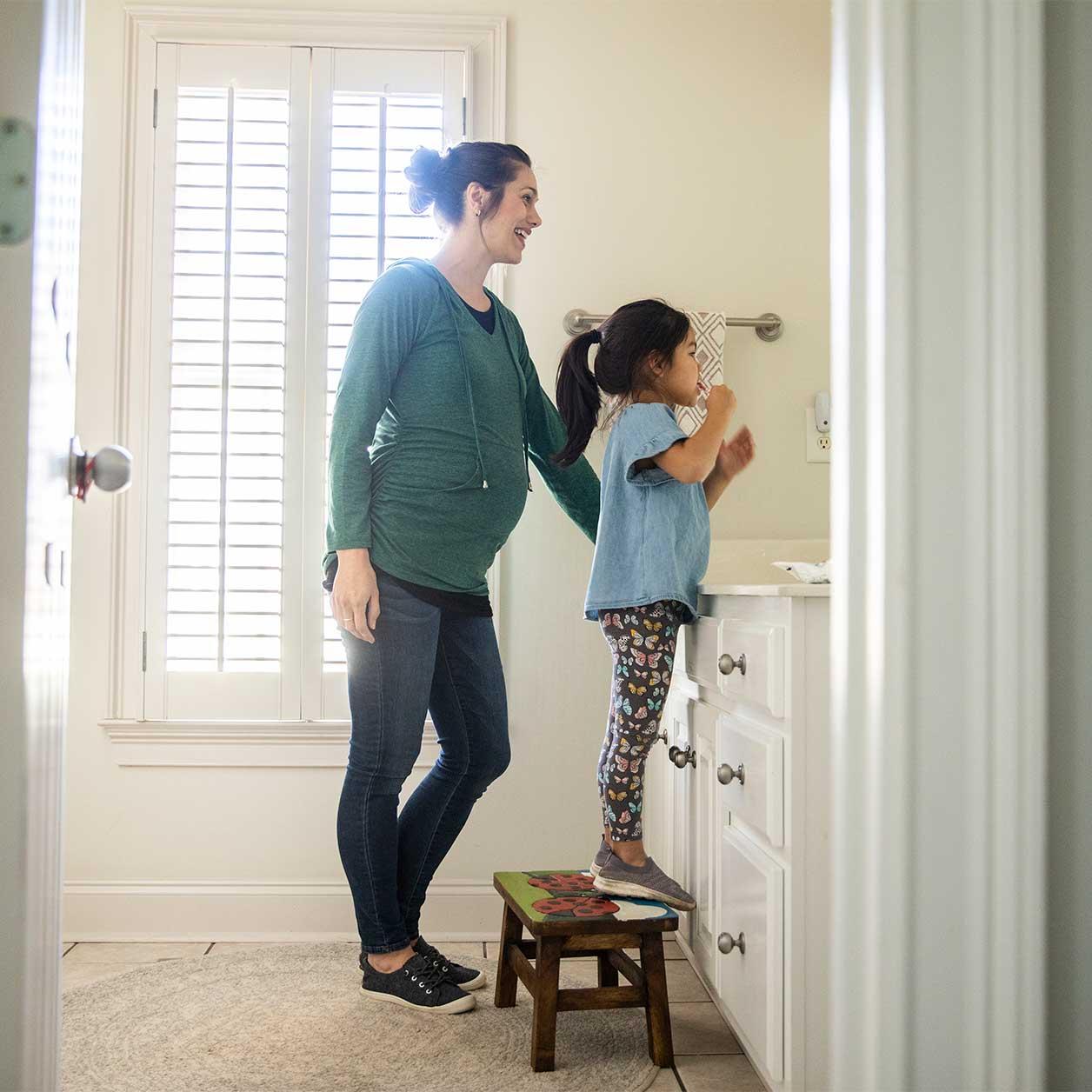 A parent helps a child brush their teeth