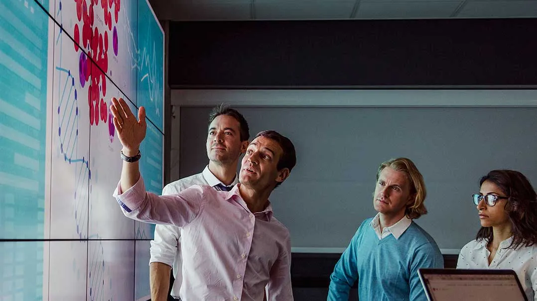 Colleagues review data on a large screen
