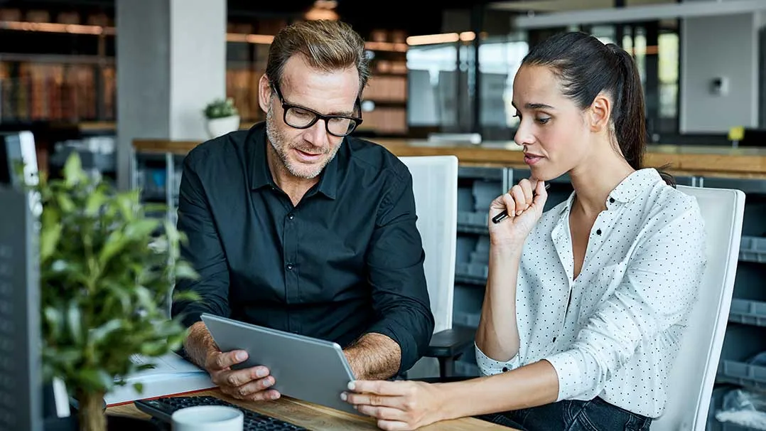 Man and woman look down at tablet
