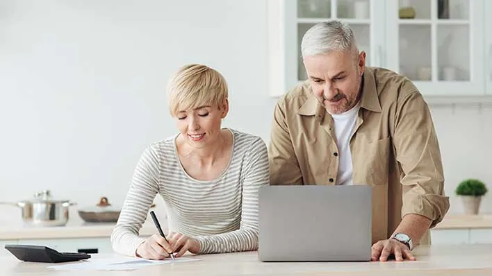 A couple reviews information on a laptop