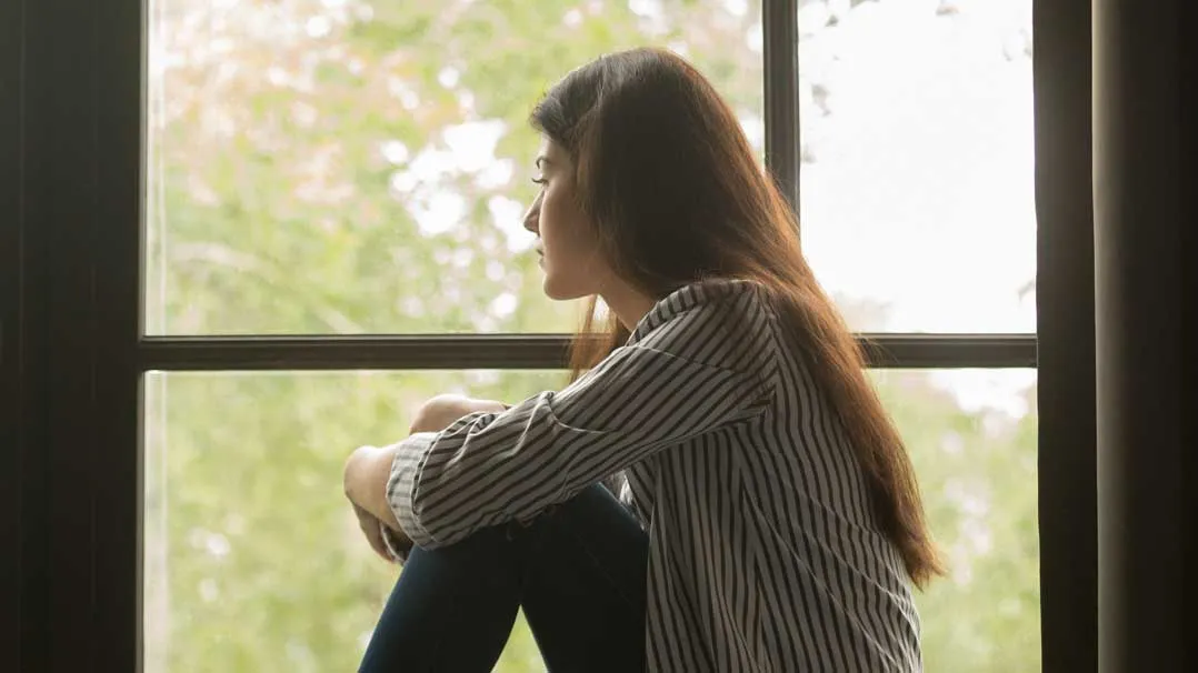 A woman looks out a window