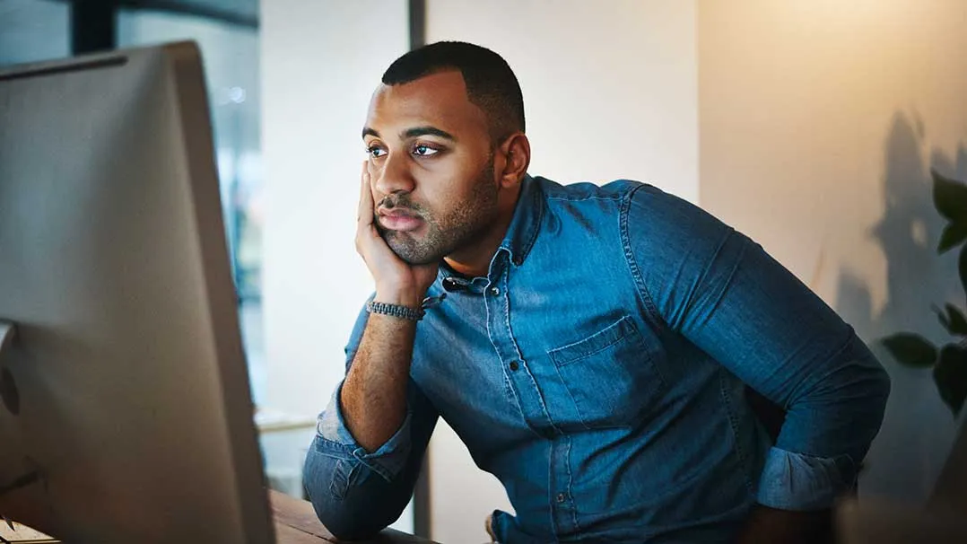 A despondent man looks at a computer screen