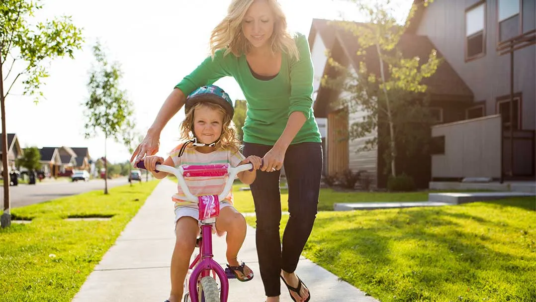 a mother teaches her child to ride a bike