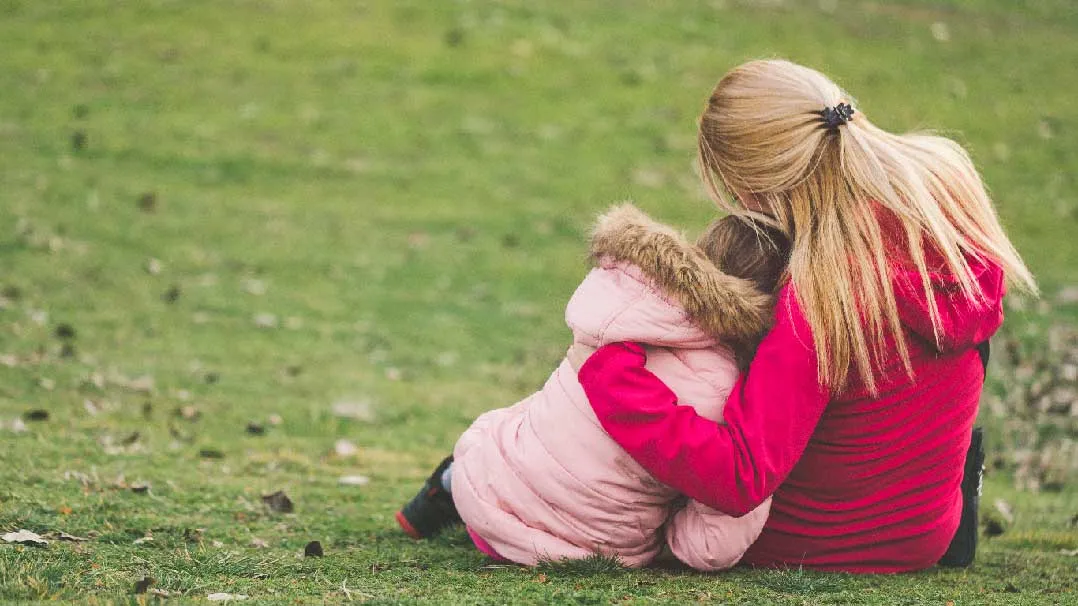 An adult hugs a child
