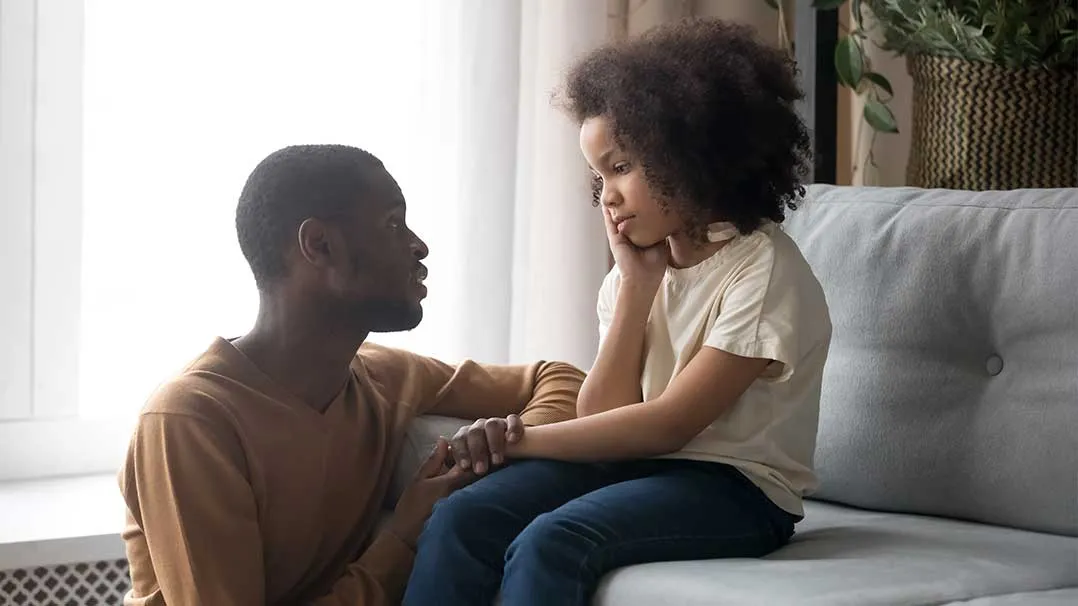 A Black parent comforts his child