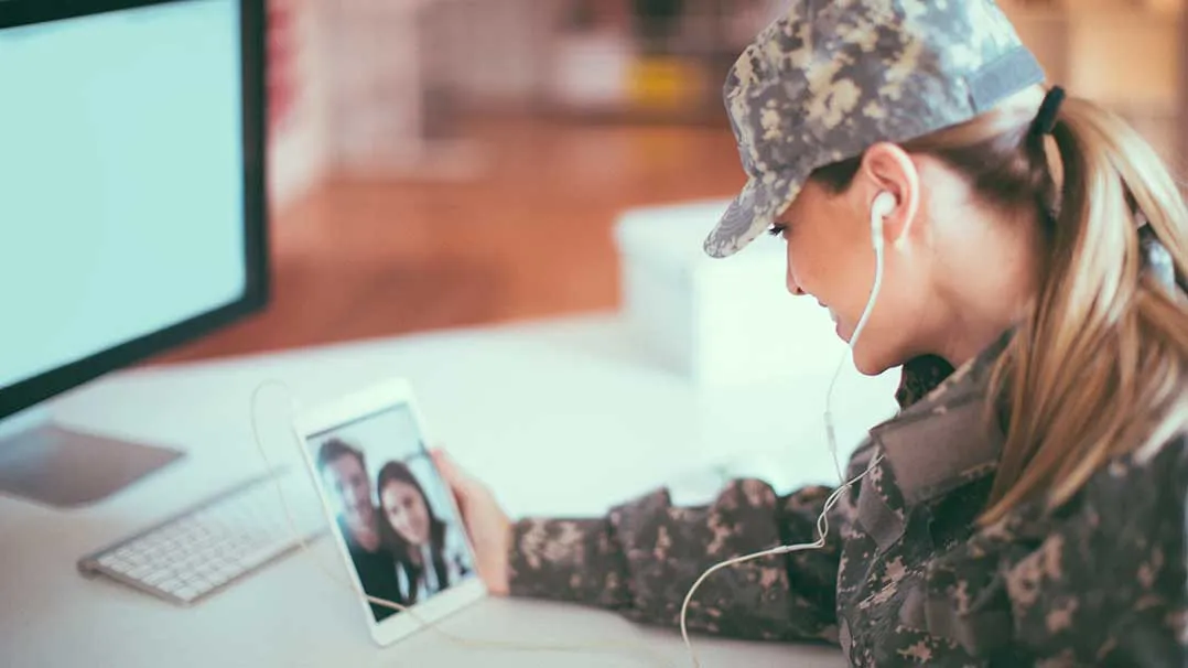 A woman in the military on a video call with family