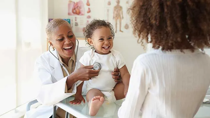 A pediatrician meets with a patient and their parent