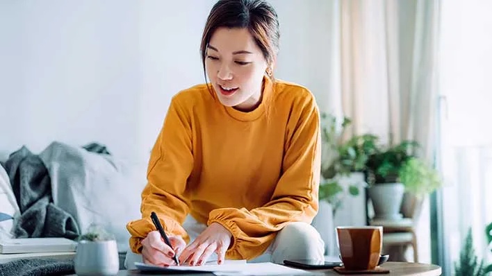A woman writes with a pen on a pad